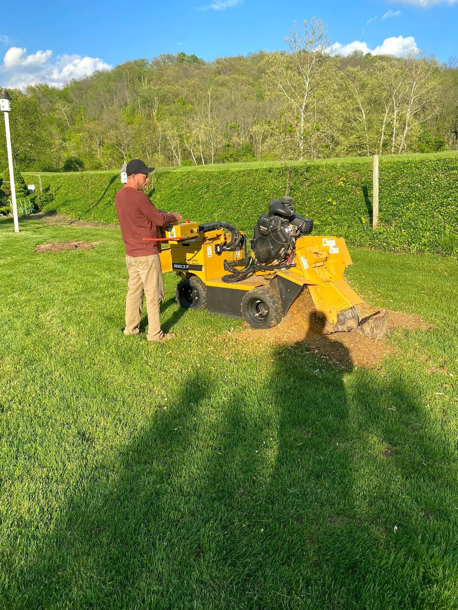 Ron operating a stump grinder on a residential lawn